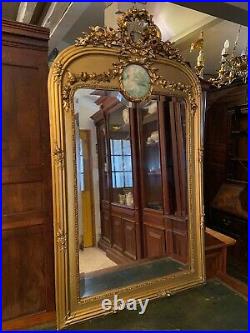 Miroir trumeau doré glace biseautée à décor de fronton style Louis XVI